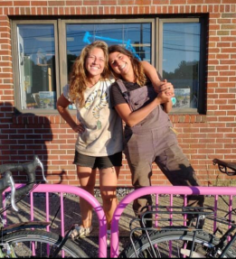 two farmers smiling in front of a bike rack